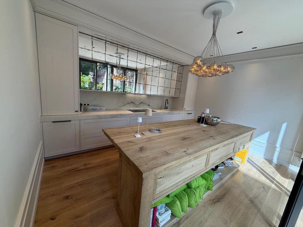 Eine moderne Küche im Landhausstil mit Spiegelrückwand und großer Insel aus Holz.